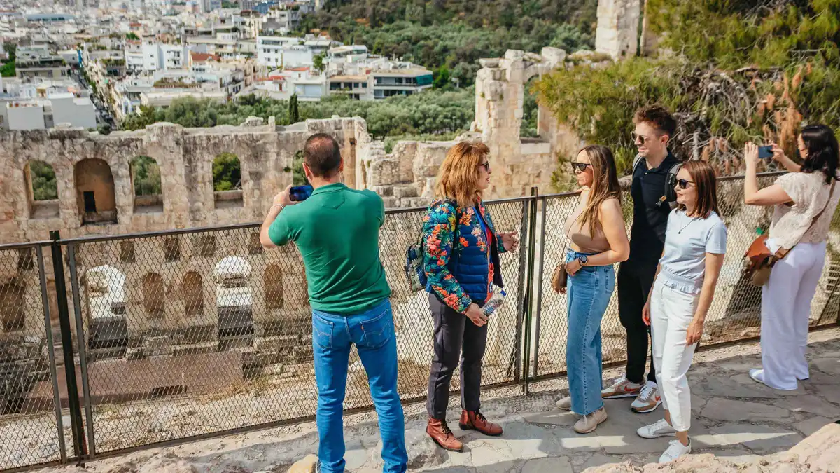 A small group with a guide on the Acropolis with the Parthenon behind them in Athens, Greece