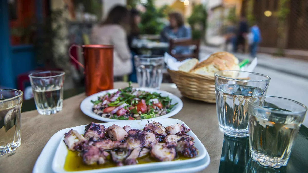 A small group tasting Greek pastries at a bakery counter on a food walking tour in Athens, Greece