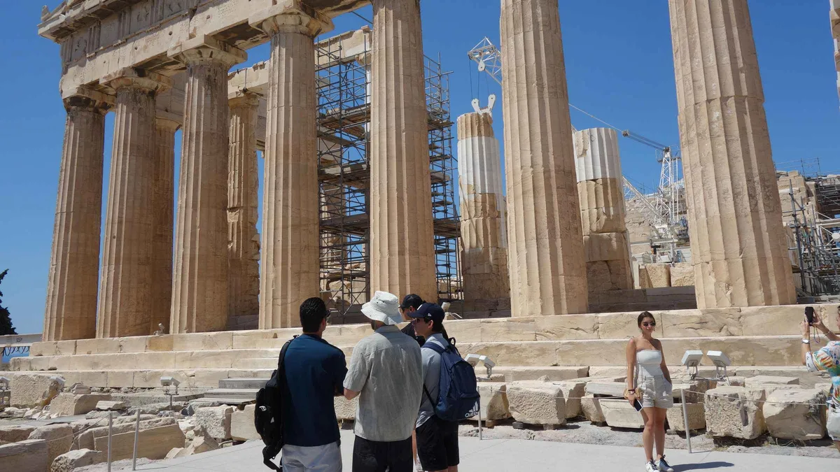 A guide of a group of eight explaining the Parthenon columns on the Acropolis in Athens, Greece