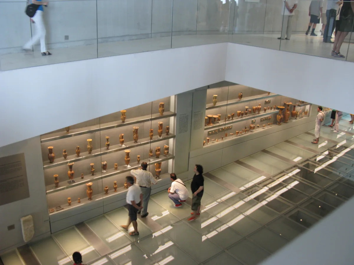 Visitors on the sloping gallery of the Acropolis Museum in Athens, Greece, with the excavation visible through the floor