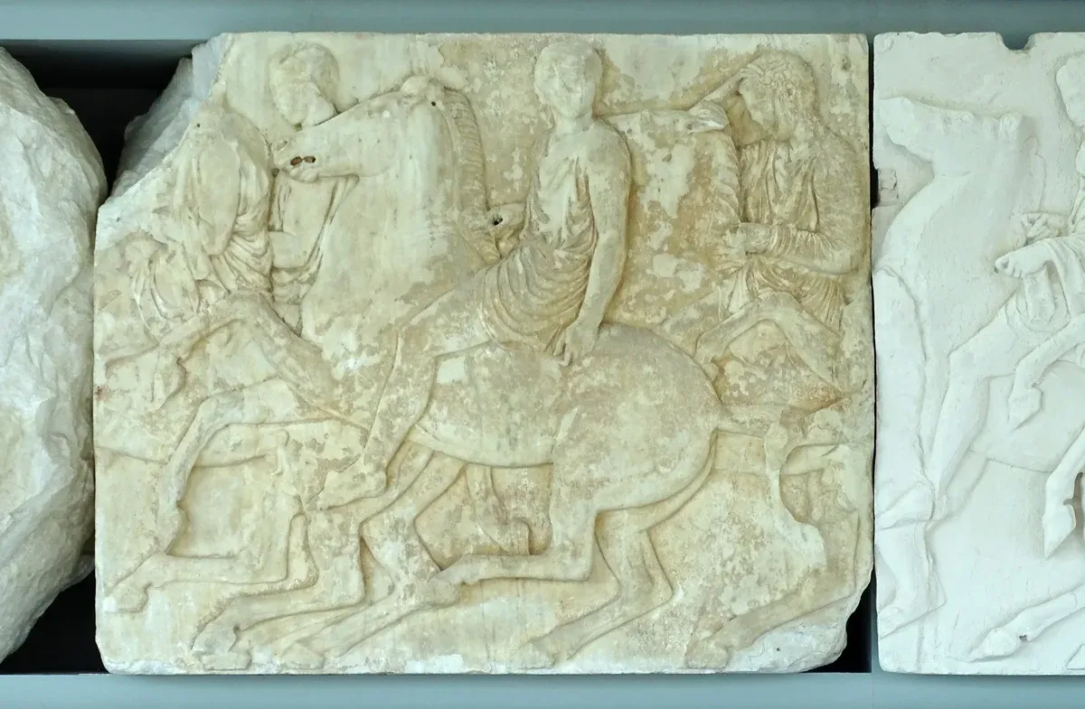 Original Parthenon frieze marble beside a white plaster cast in the Acropolis Museum, Athens, Greece